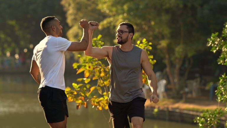 Two men in fitness gear greeting each other outdoors