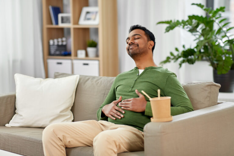 pleased indian man eating takeaway food at home